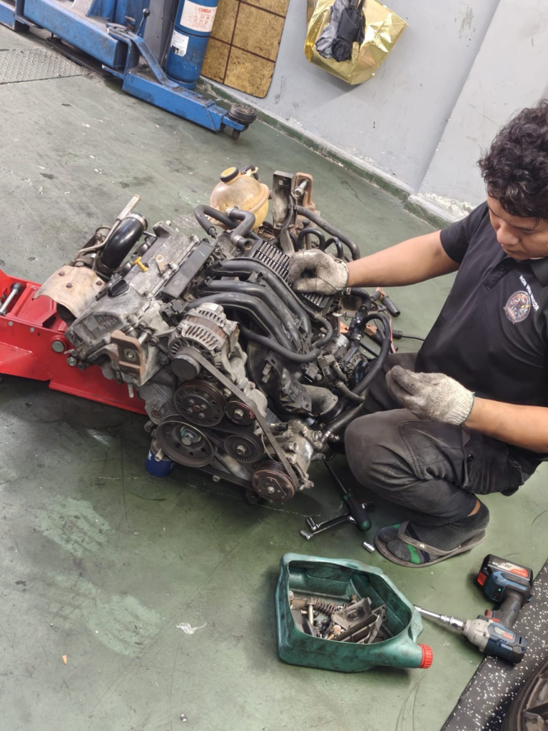 Hon Win Motor mechanic working on an engine removed from a car